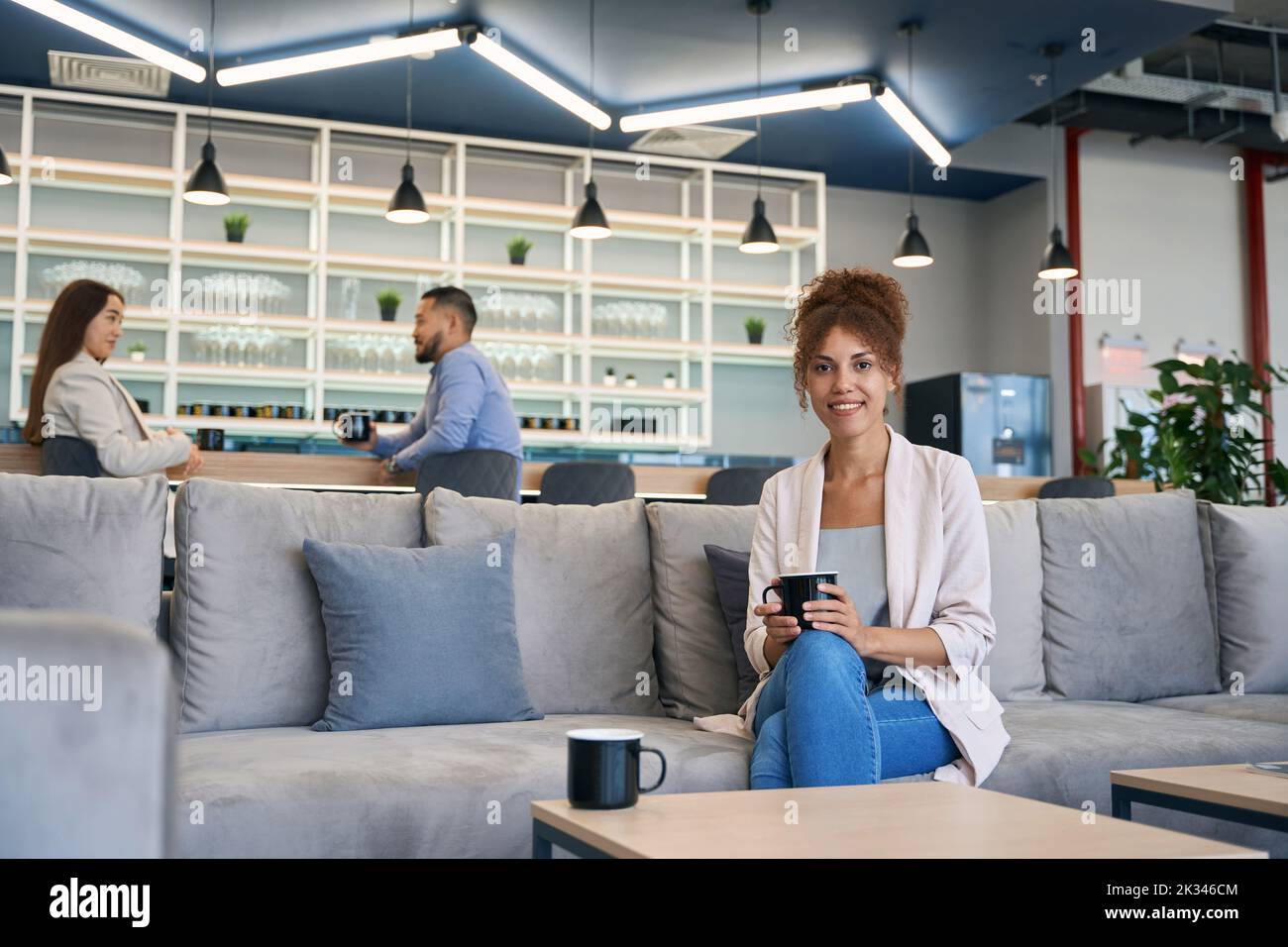 Cheerful young woman enjoying her work break in co-working space Stock Photo