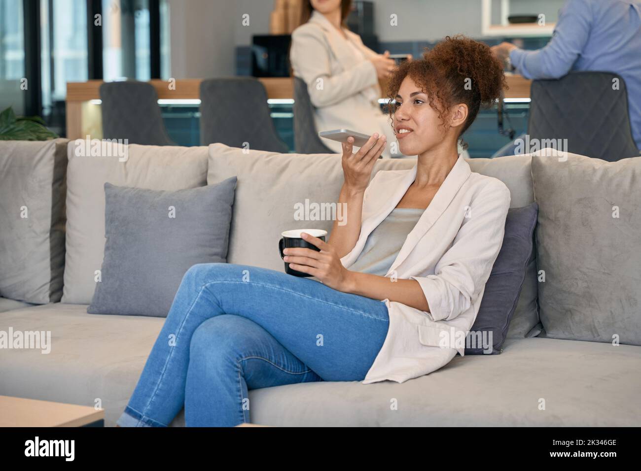 Woman talking on cellphone in co-working space Stock Photo
