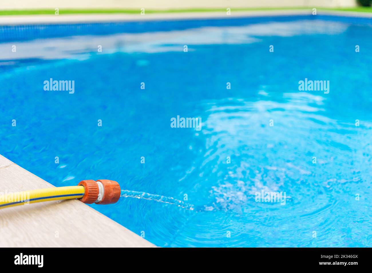 swimming pool being filled with water with a garden hose at summer