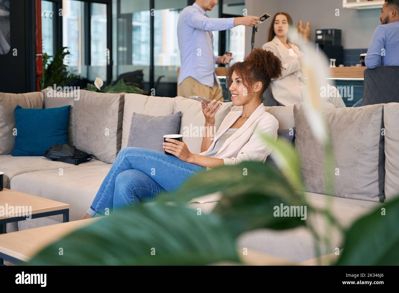 Cheerful lady having smartphone conversation in co-working space Stock Photo