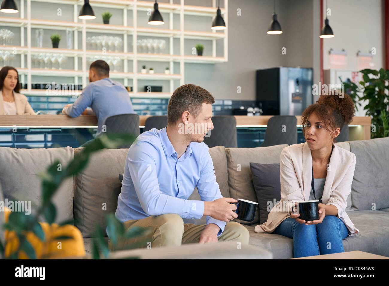Woman and her colleague sitting on sofa at coffee break Stock Photo