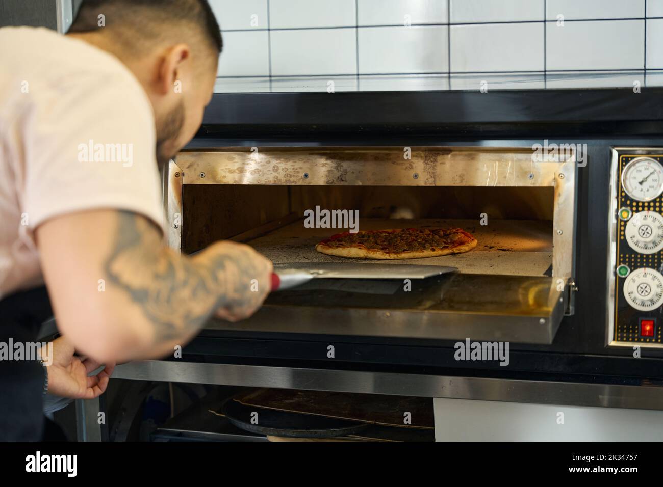 Hard-working man cooking delicious pizza in the oven Stock Photo