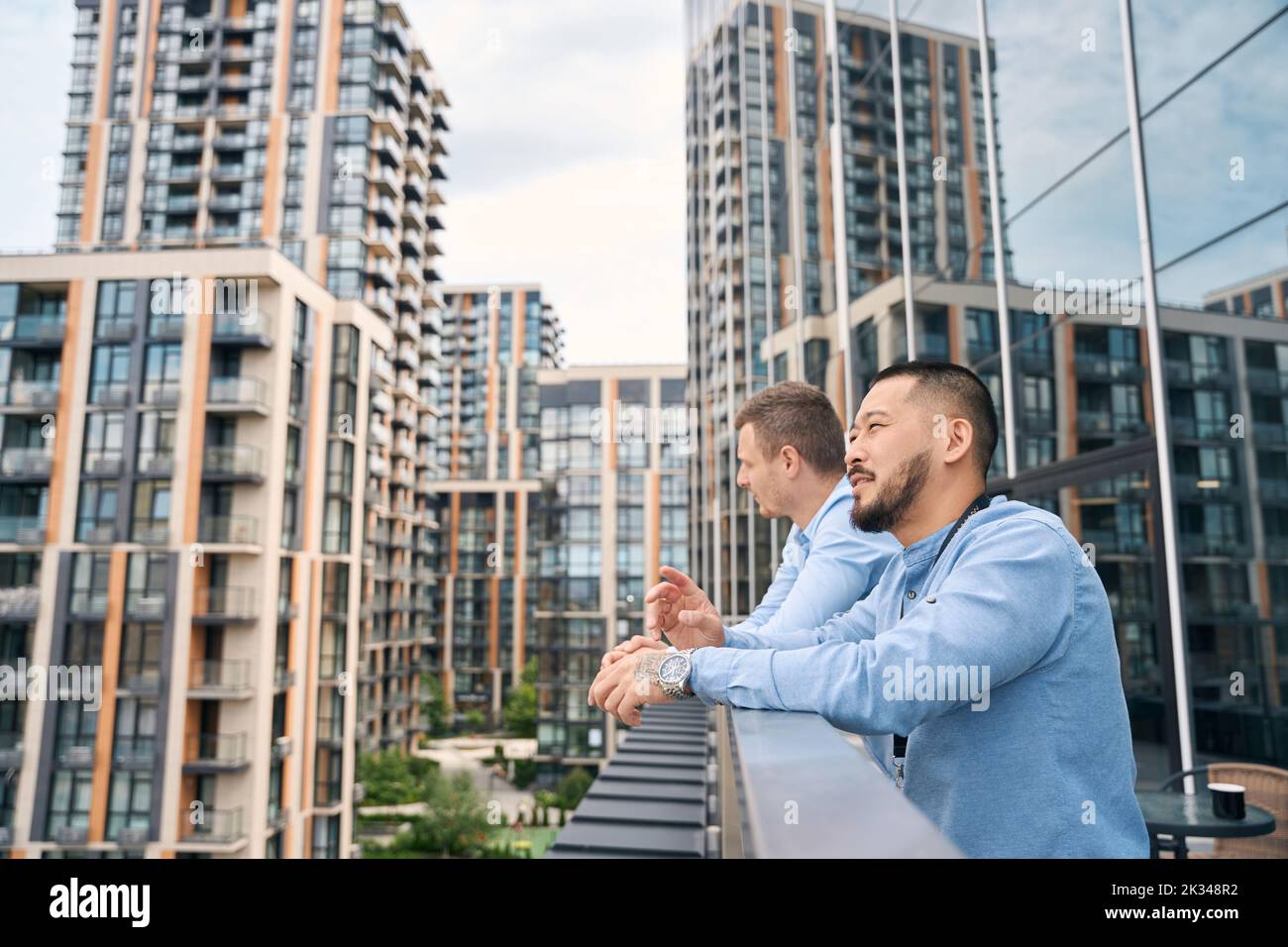 Two thoughtful company employees standing on office balcony Stock Photo