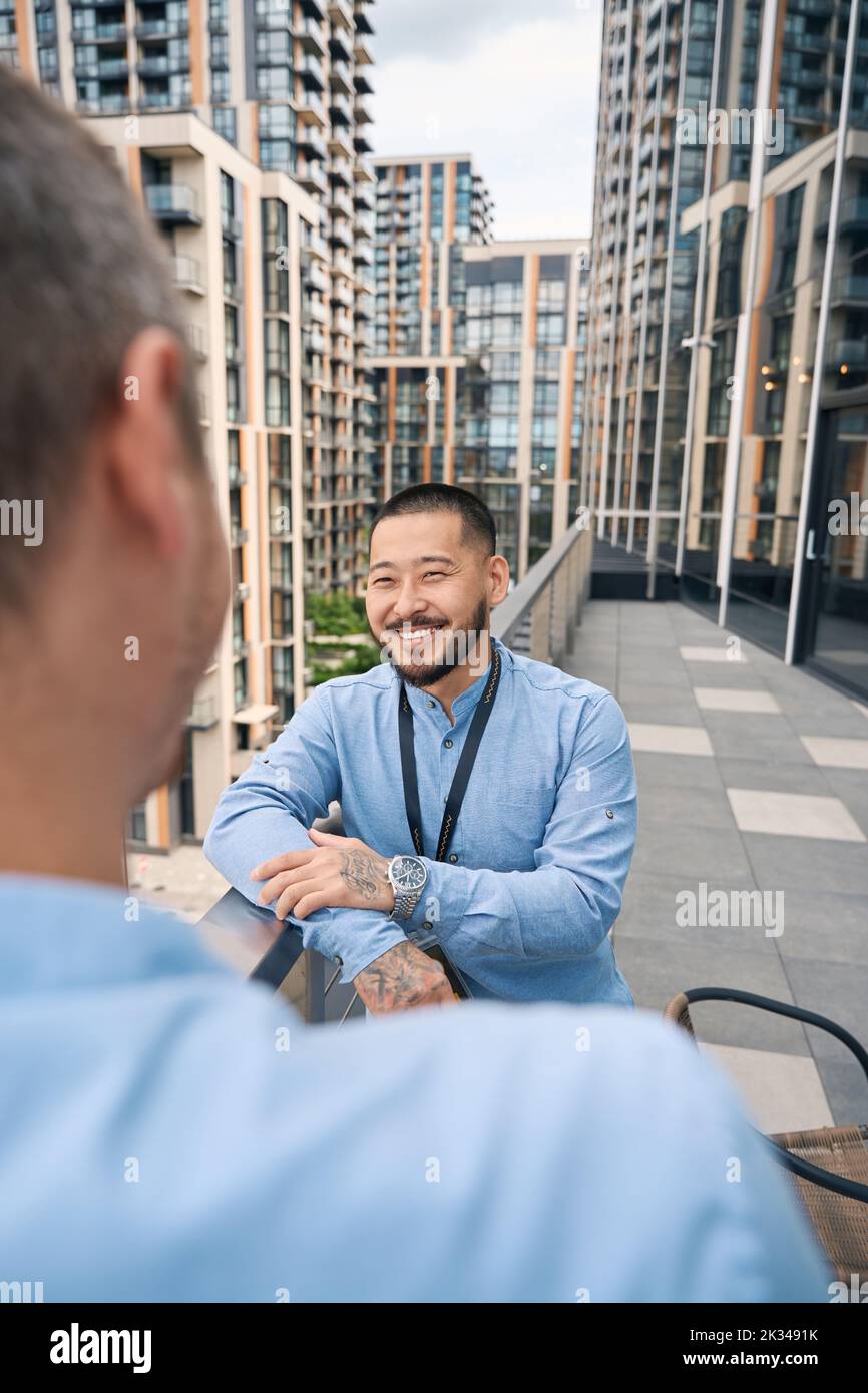 Young office employee chatting with his coworker outdoors Stock Photo