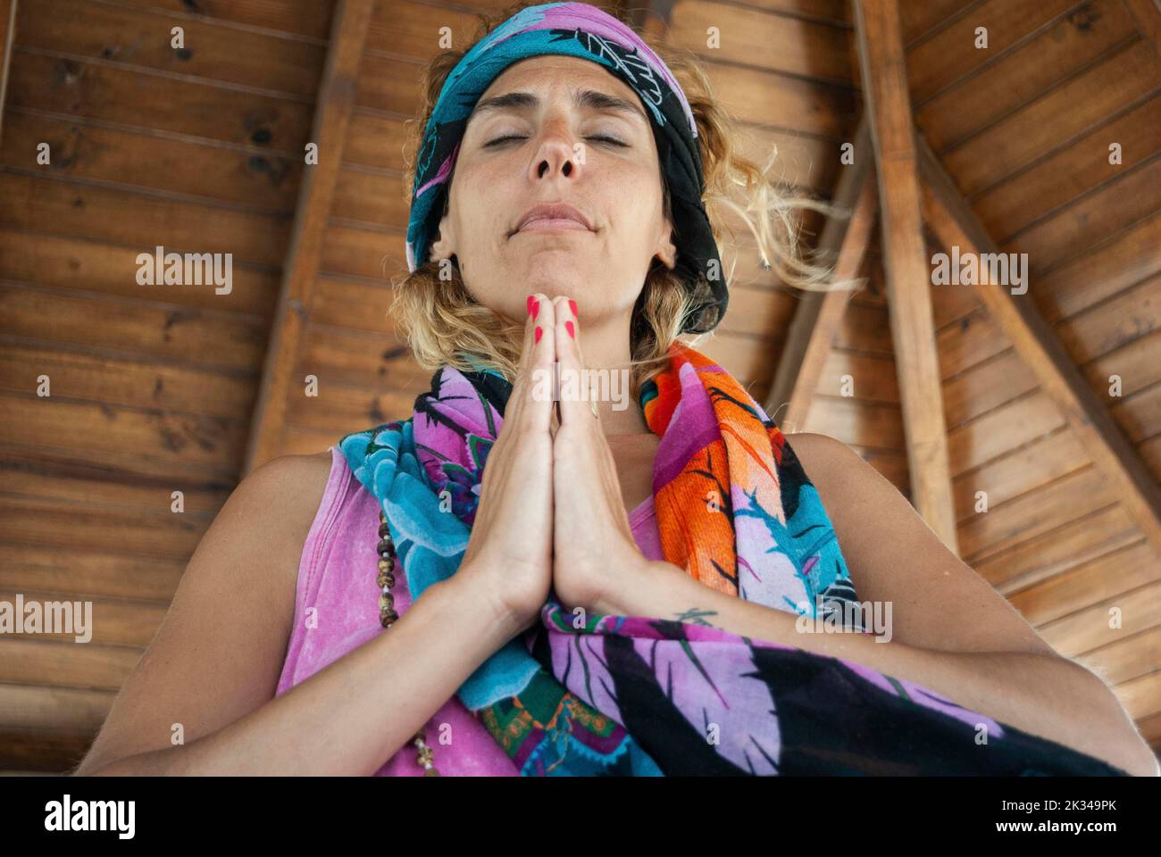 Low angle view of a woman clasping hands and wearing a bandana while meditating Stock Photo