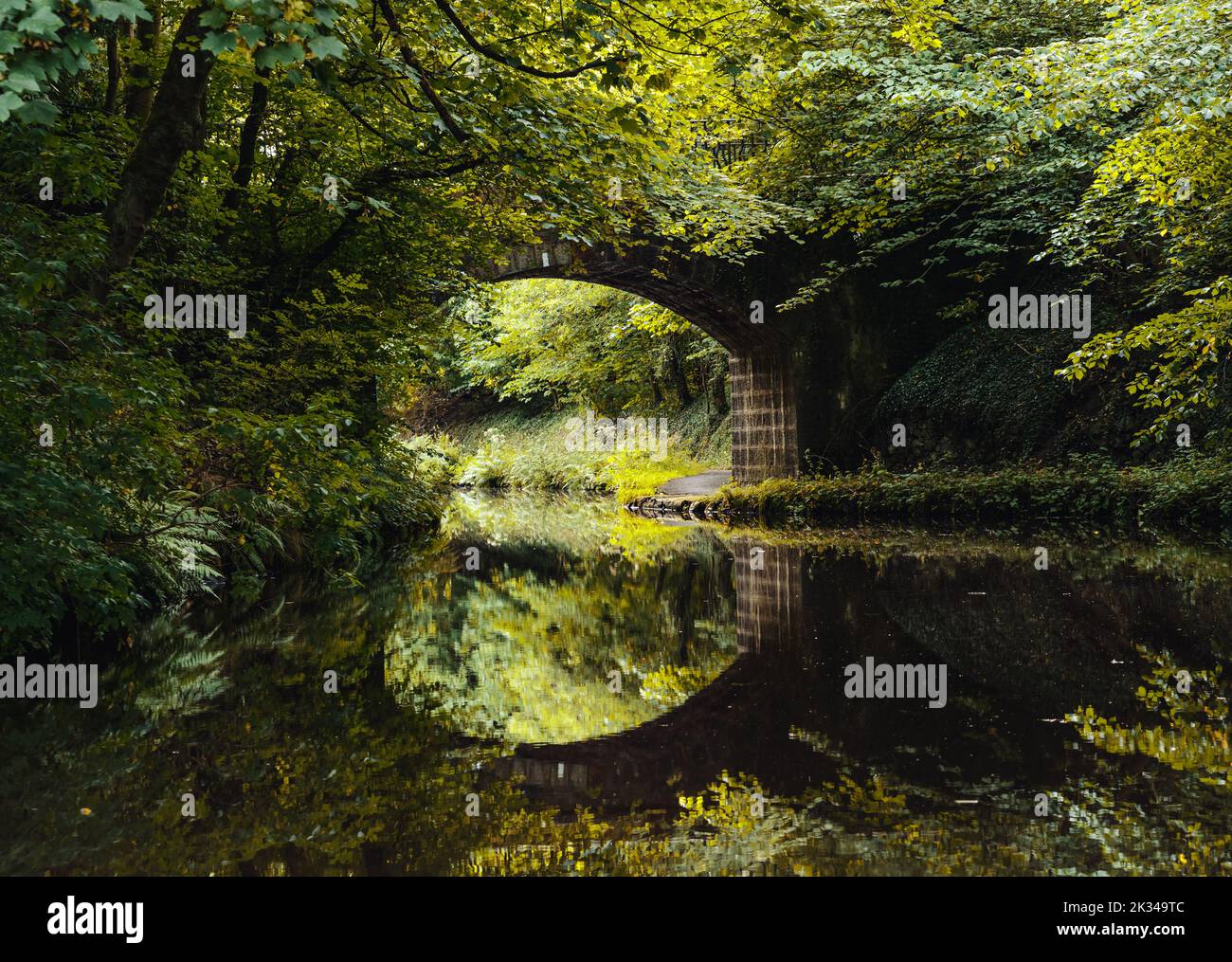 An arched stone bridge reflected in water on the Union Canal, Scotland, UK Stock Photo