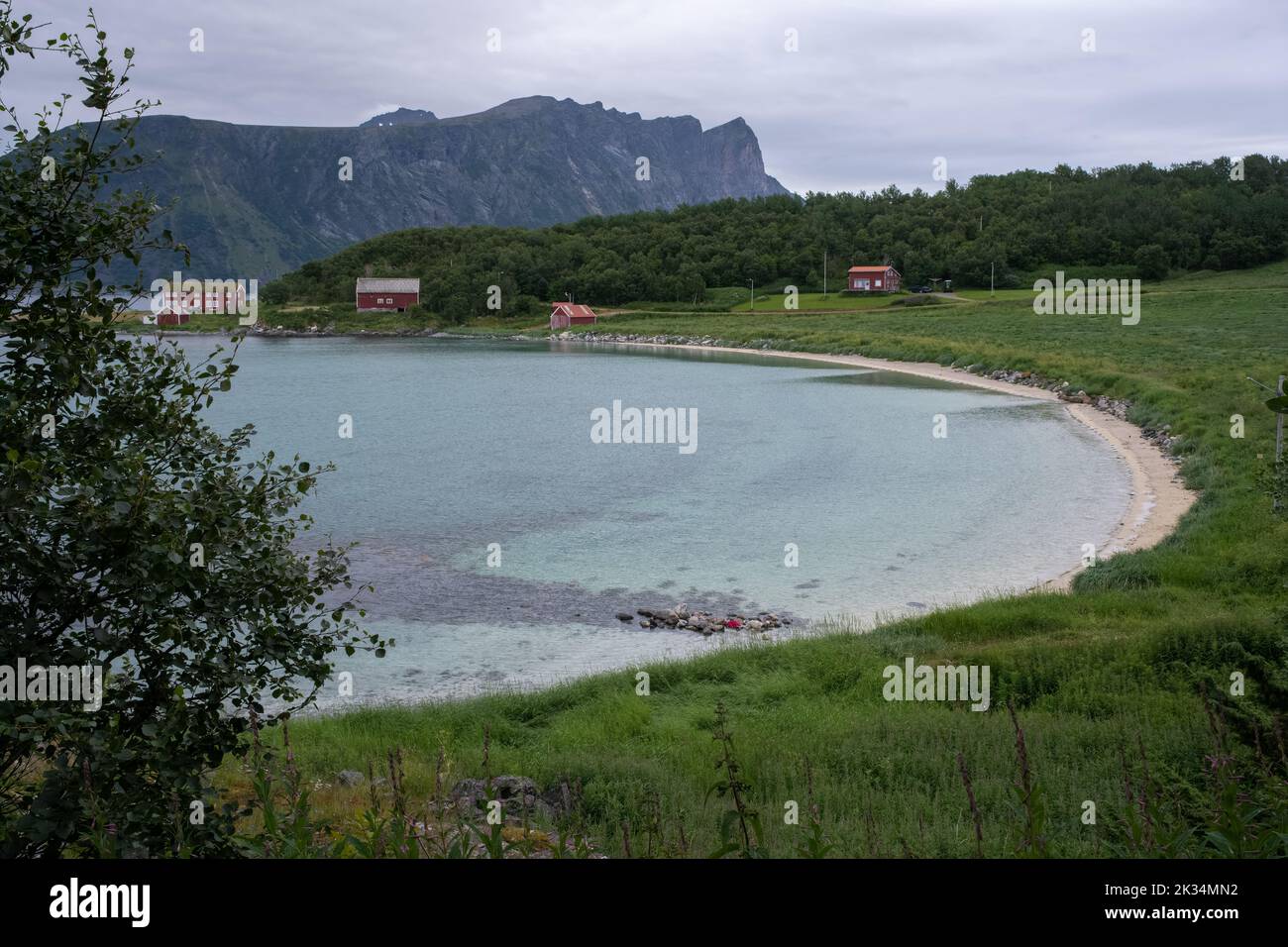 Wonderful landscapes in Norway. Nordland. Beautiful scenery of a coastline from Elgsnes beach. Rippled sea in a cloudy summer day. Traditional red hou Stock Photo