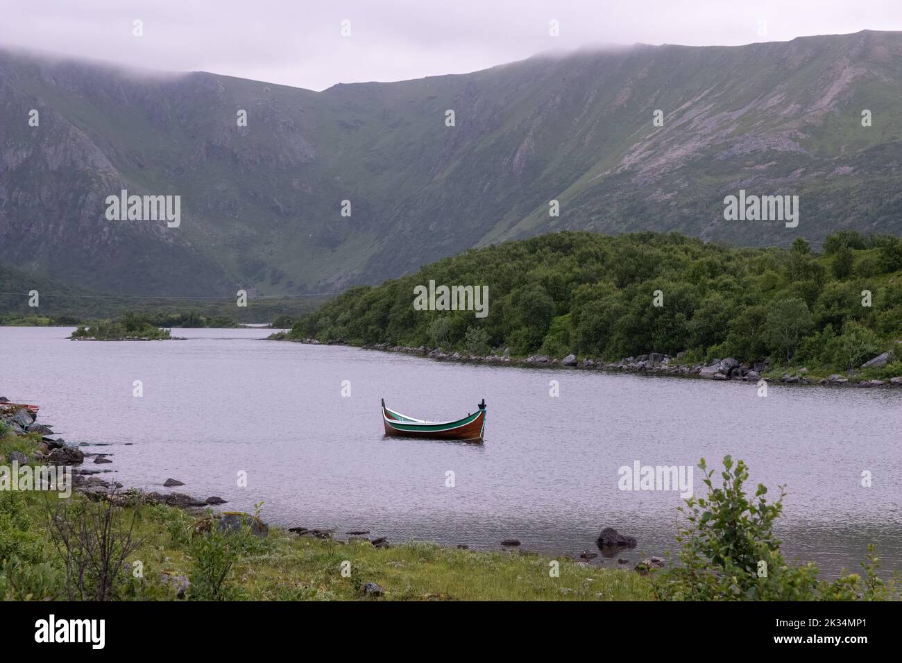 Wonderful landscapes in Norway. Nordland. Beautiful scenery of a valley with a picturesque boat in the Storvatnet lake. Rippled water in a cloudy summ Stock Photo