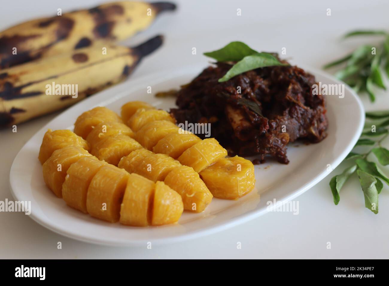 Mutton roast and steamed ripe plantain. A spicy and sweet combination with spicy mutton roast prepared in Kerala style and steamed plantain. Shot on w Stock Photo