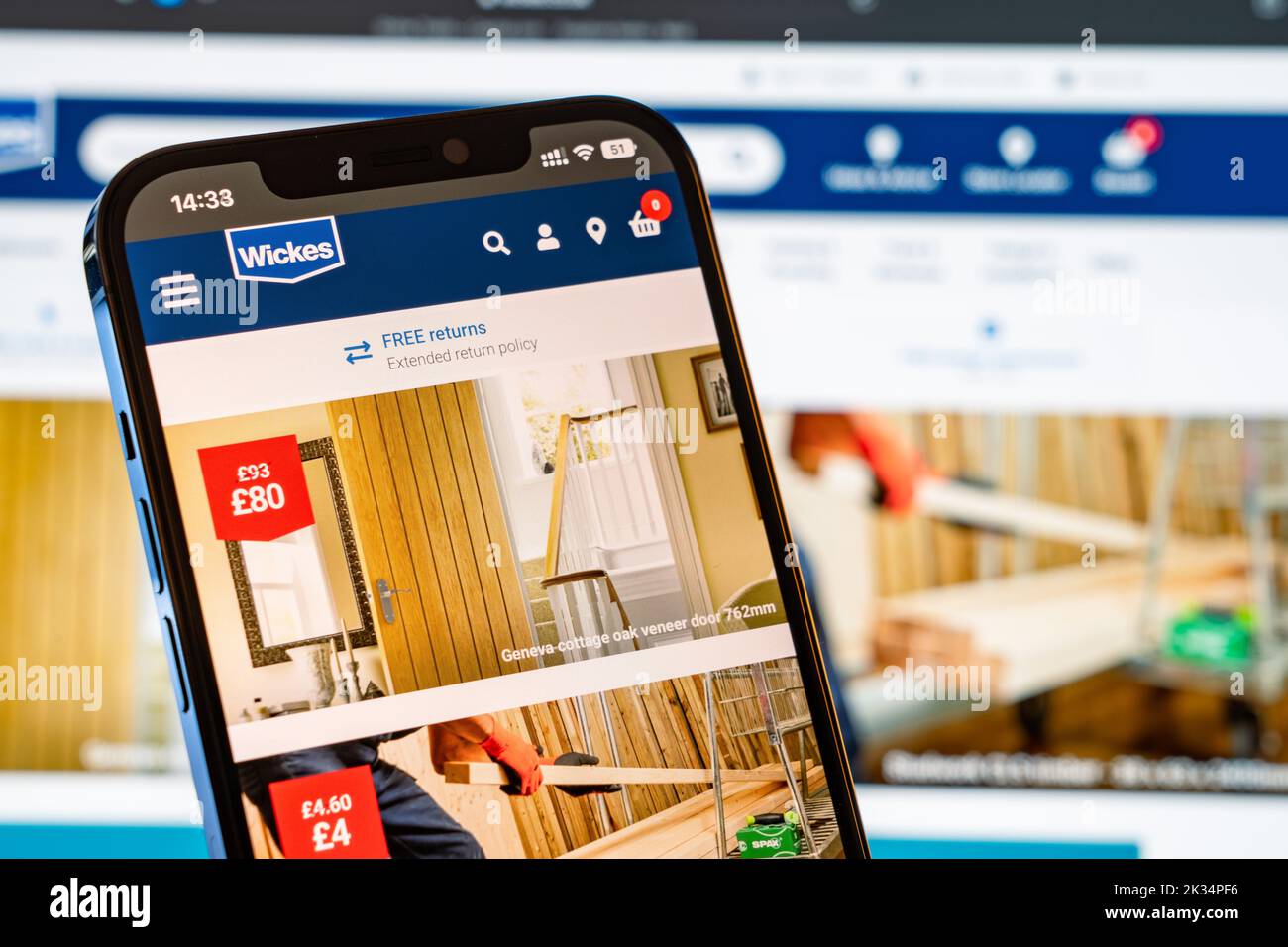 Wickes Mobile Website with laptop website in the background Stock Photo