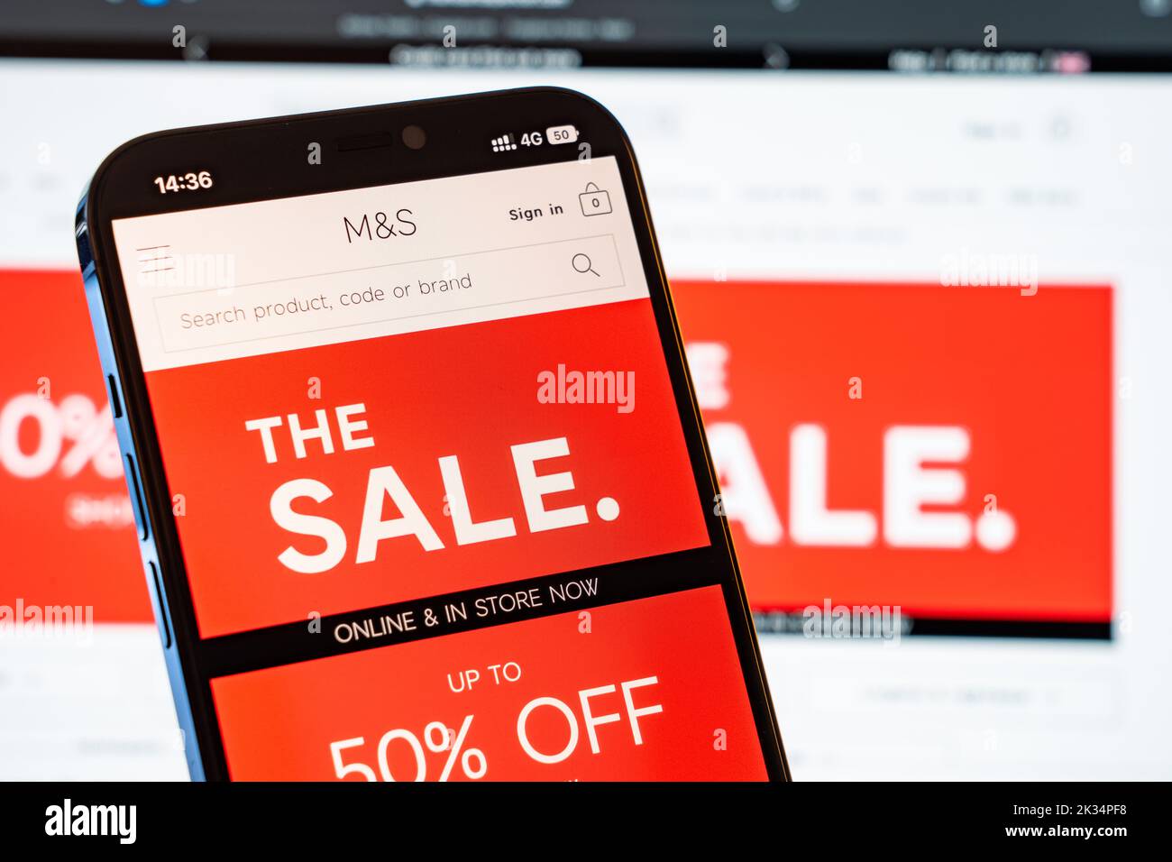 M&S Marks and Spencer Mobile Website with laptop website in the background Stock Photo