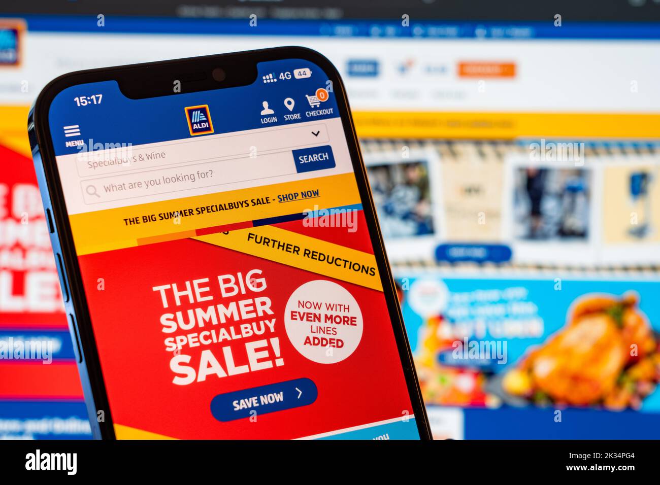 Aldi Mobile Website with laptop website in the background Stock Photo