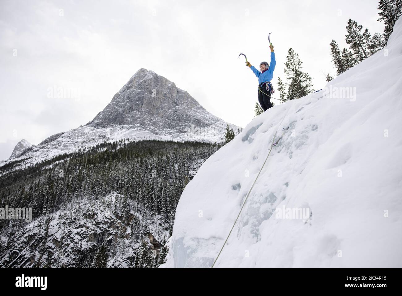 Ice climber rejoicing on peak of mountain Stock Photo