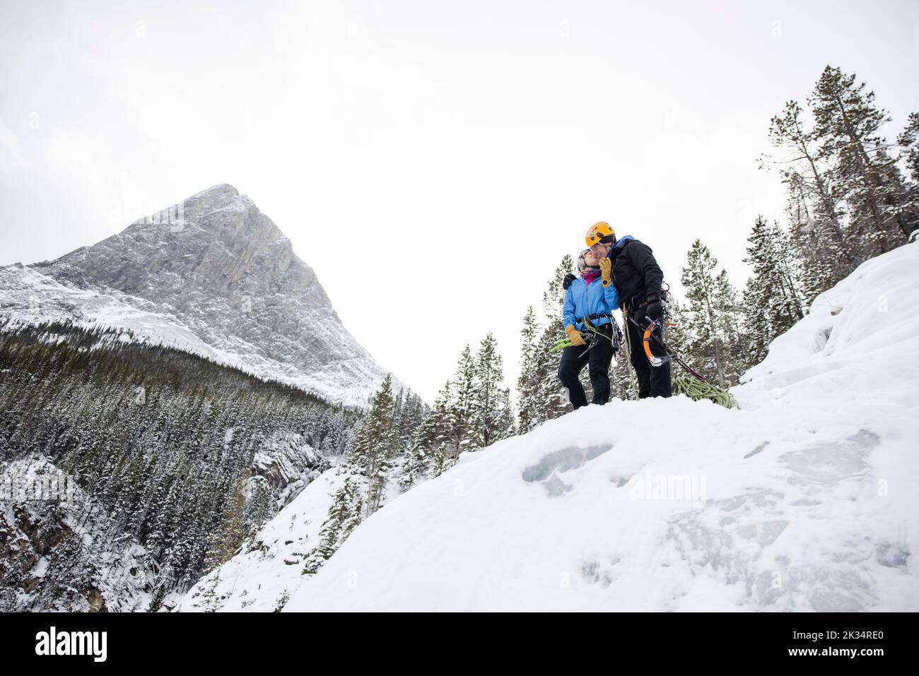 Ice climbers kissing on peak of snowy mountain Stock Photo