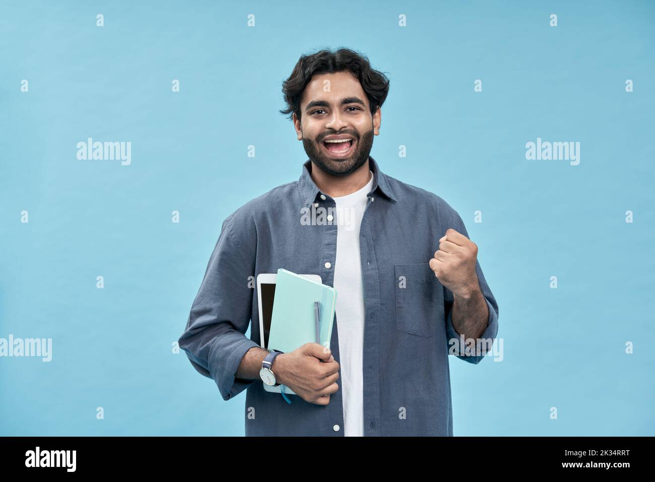 Happy arab young man student winner isolated on blue celebrating scholarship. Stock Photo