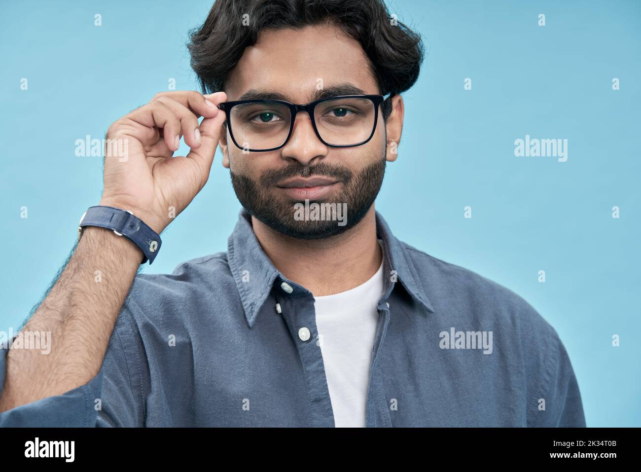 Confident arab young man wearing eyeglasses isolated on blue background. Stock Photo