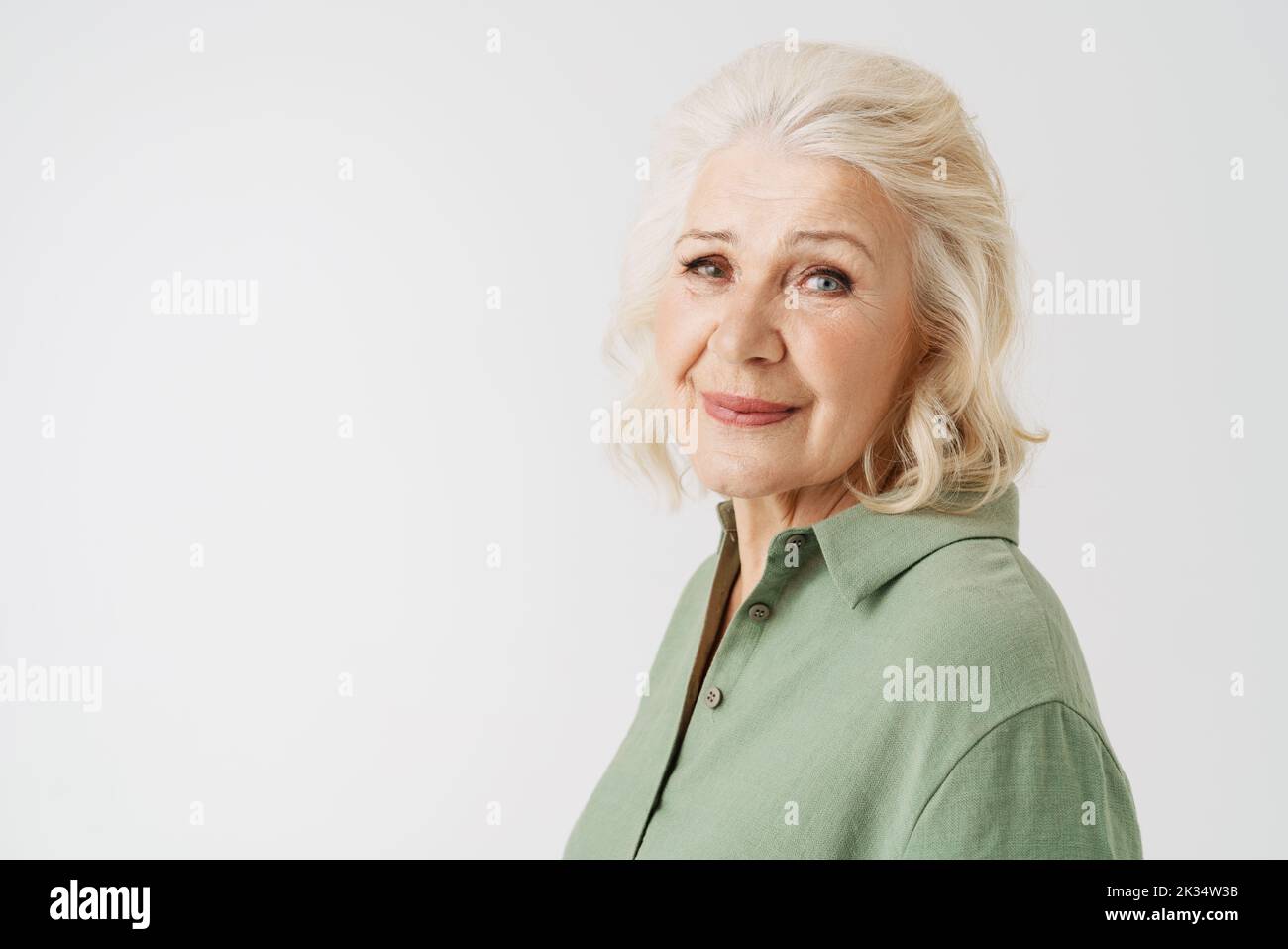 Grey senior woman in shirt smiling and looking at camera isolated over white background Stock Photo