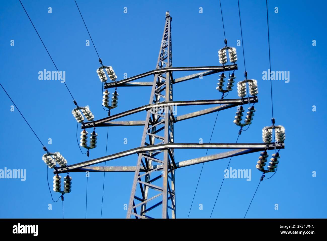 High voltage power pylons against blue sky and sun rays Stock Photo - Alamy