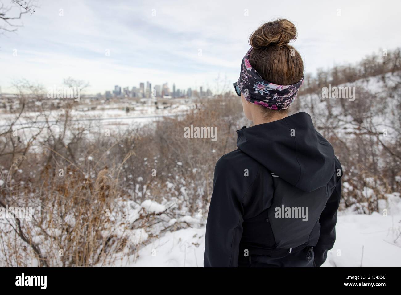 Rear view of female runner looking out at city in distance Stock Photo ...