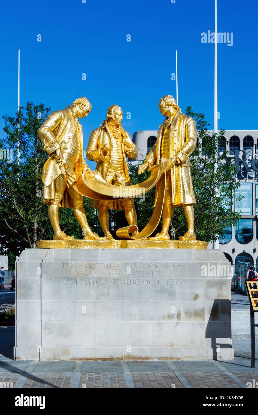 trio gold, bronze, statue engineers James Watt, Matthew Boulton & William Murdoch against blue sky in Centenary Square, Birmingham, UK. Stock Photo