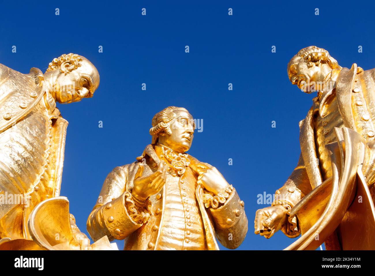 looking up trio gold, bronze, statue engineers James Watt, Matthew Boulton & William Murdoch against blue sky in Centenary Square, Birmingham, UK. Stock Photo