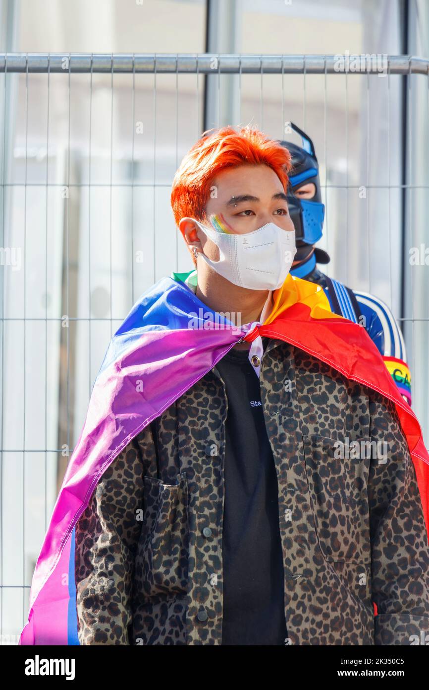 masked asian gay man draped in LGBT flag at Gay Pride parade protest 2022 in birmingham city centre uk september 24th Stock Photo