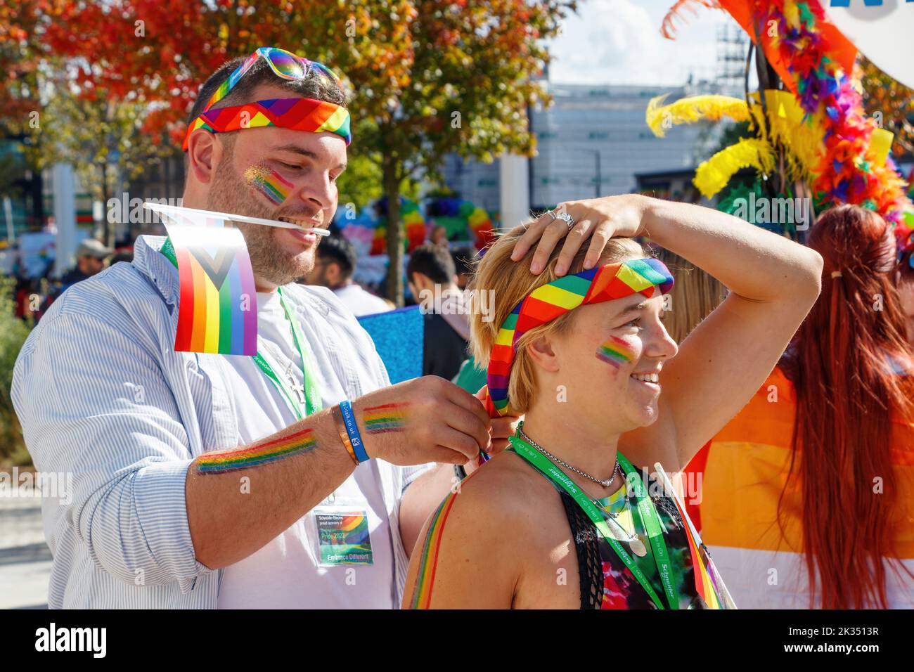 man adjusts rainbow accessories and headbands on woman at Gay Pride parade protest 2022 in birmingham city centre uk september 24th Stock Photo