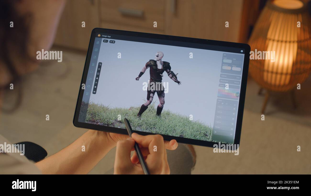 Male 3D designer creating 3D animation of video game character in design application on modern digital tablet computer using stylus Stock Photo