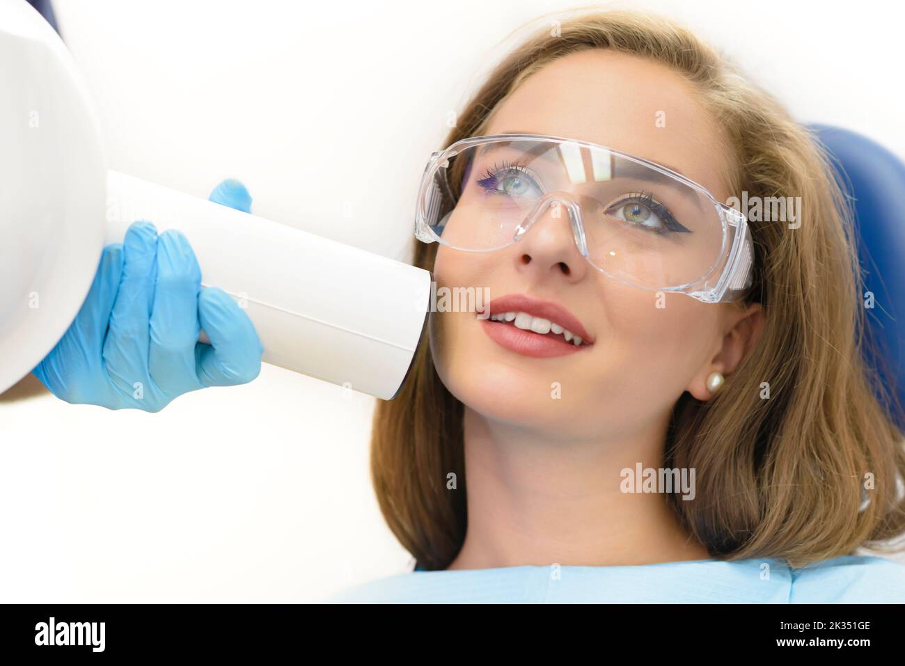 Beautiful young woman patient getting dental radiography. Dentist doctor using radiology equipment. Stock Photo