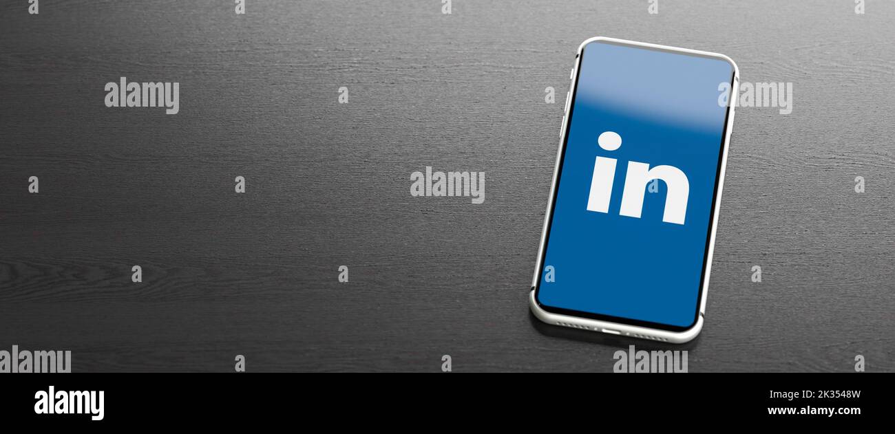 Logo of the business social media site and app LinkedIn on a mobile phone on a table. Copy space. Web banner format. Stock Photo