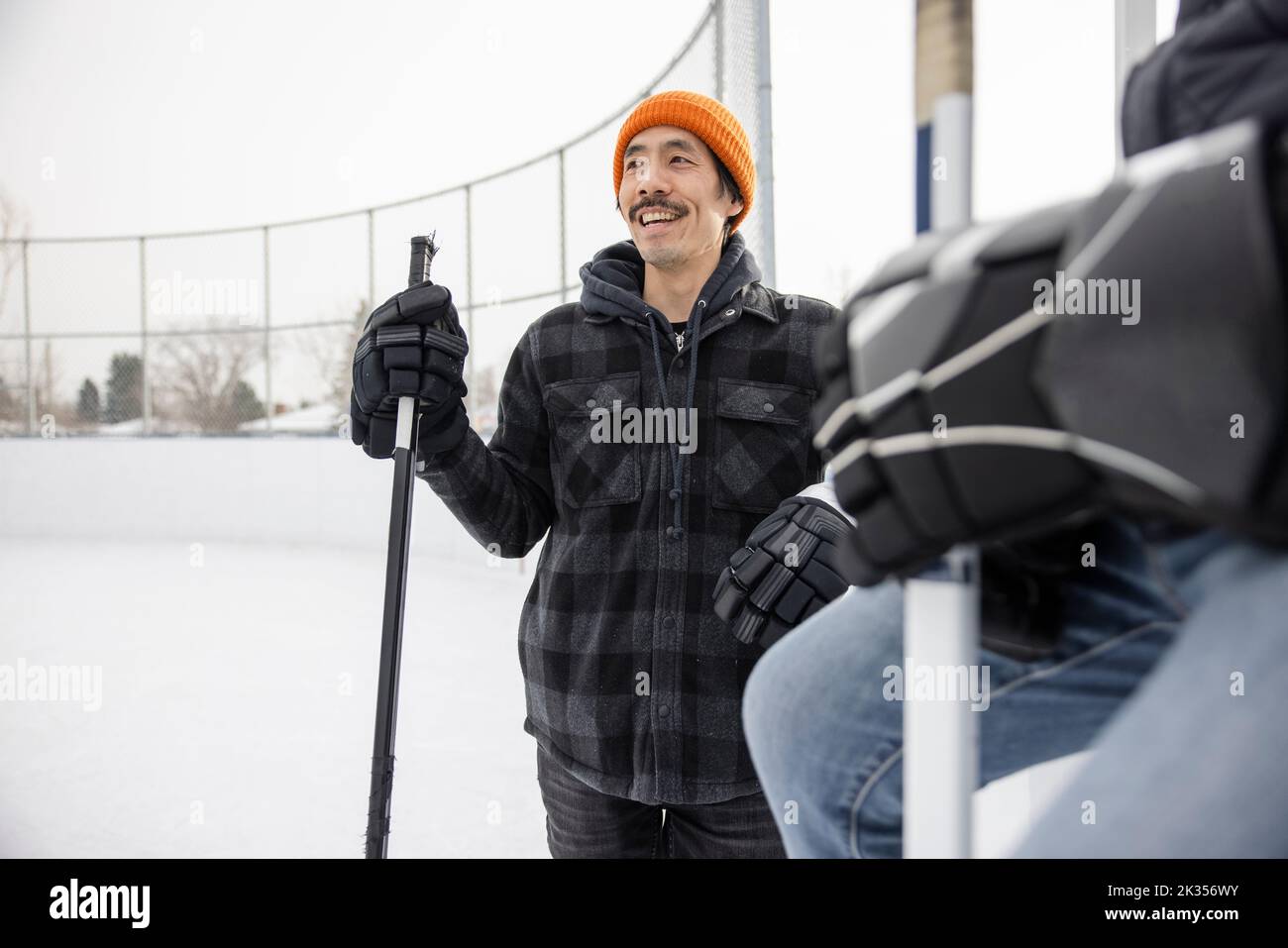 Happy man with hockey stick taking a break from ice hockey at ice rink