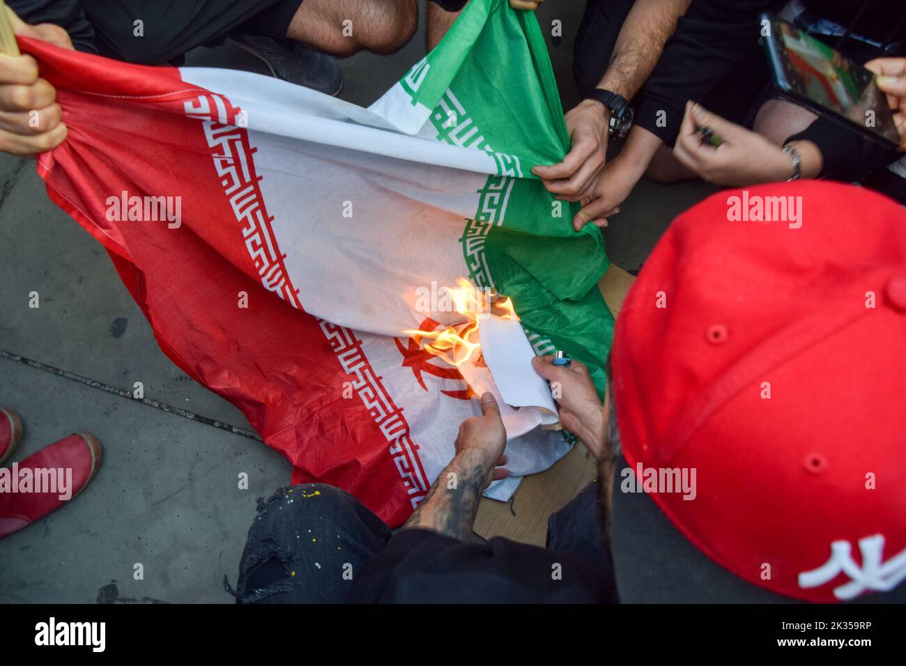 London, UK. 24th Sep, 2022. Protesters burn an Islamic Republic of Iran flag. Thousands of Iranians and other protesters gathered in Trafalgar Square in response to the death of Mahsa Amini, who died in police custody in Iran after being detained for allegedly not wearing a head scarf (hijab) "properly" in public. Credit: Vuk Valcic/Alamy Live News Stock Photo