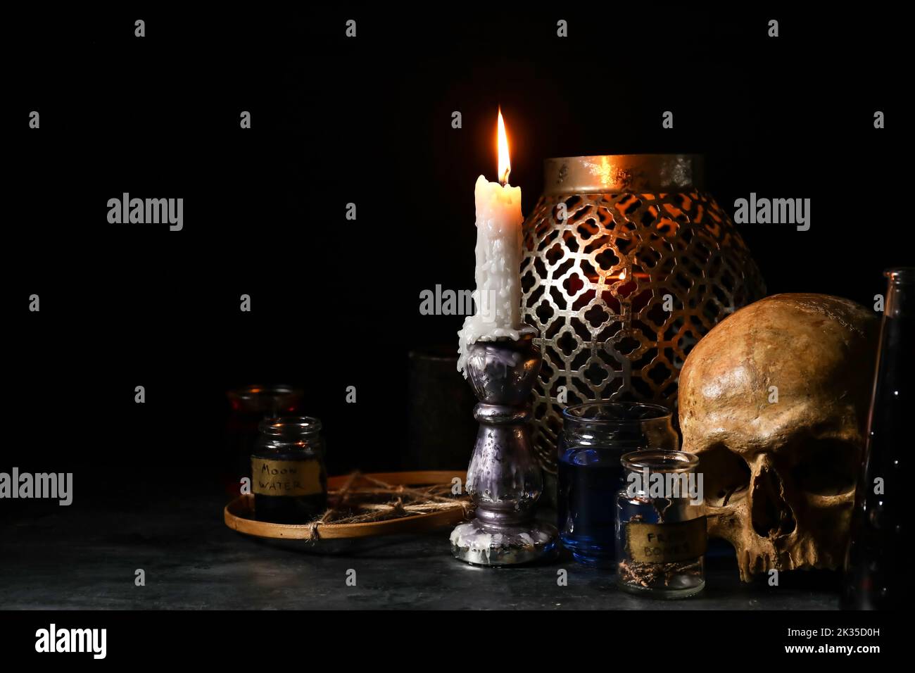 Burning candle, scull and magic attributes for ritual on dark