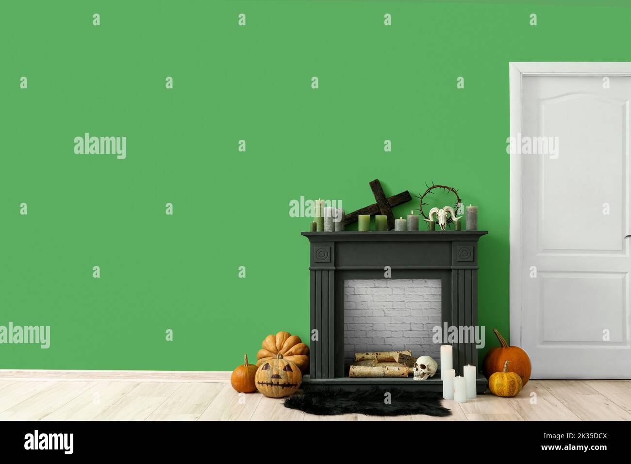 Black fireplace with candles and Halloween decor near green wall in