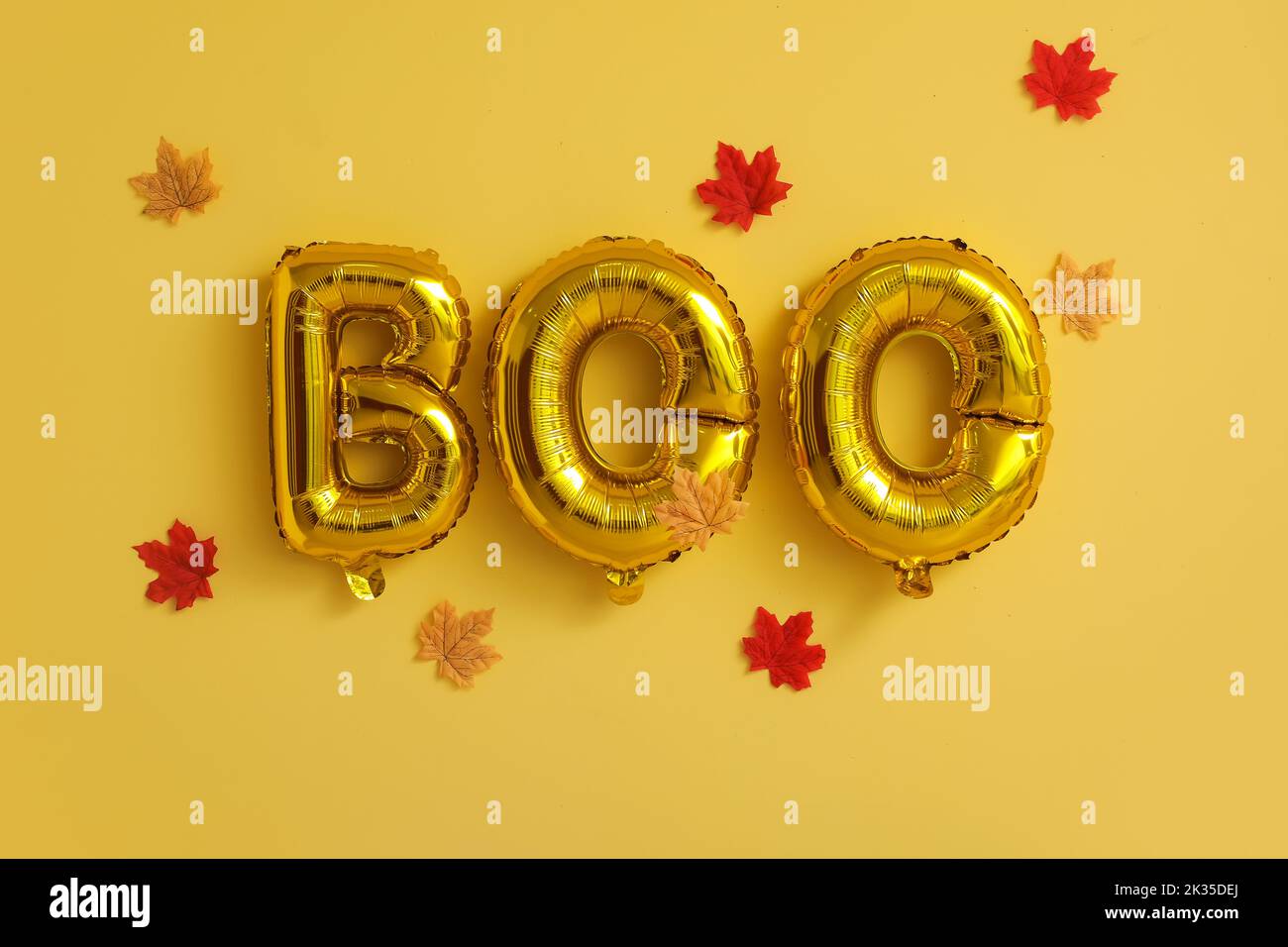 Word BOO made of balloons and fallen leaves on yellow background ...