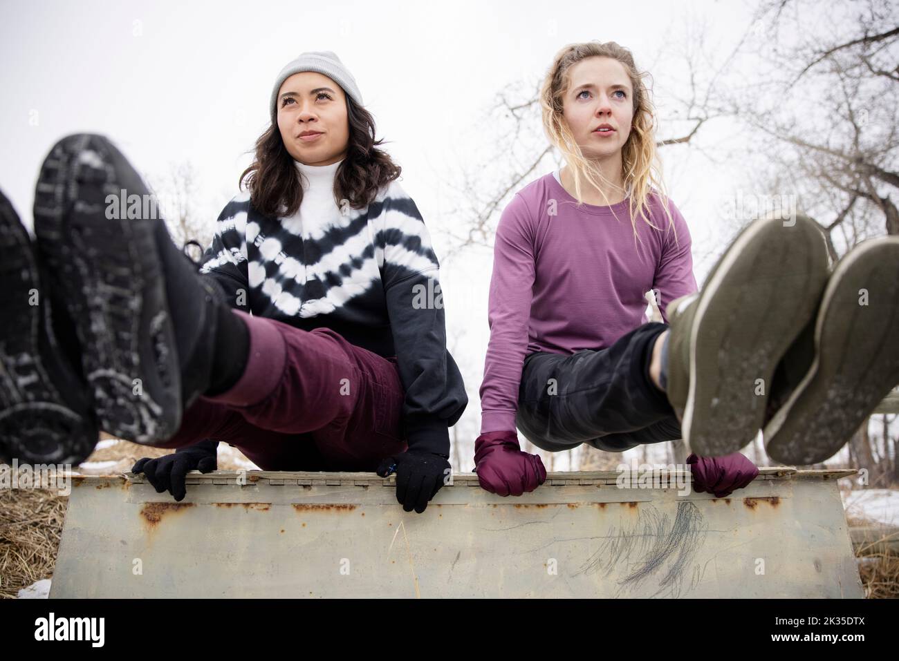 Female friends doing L-sit on concrete box Stock Photo