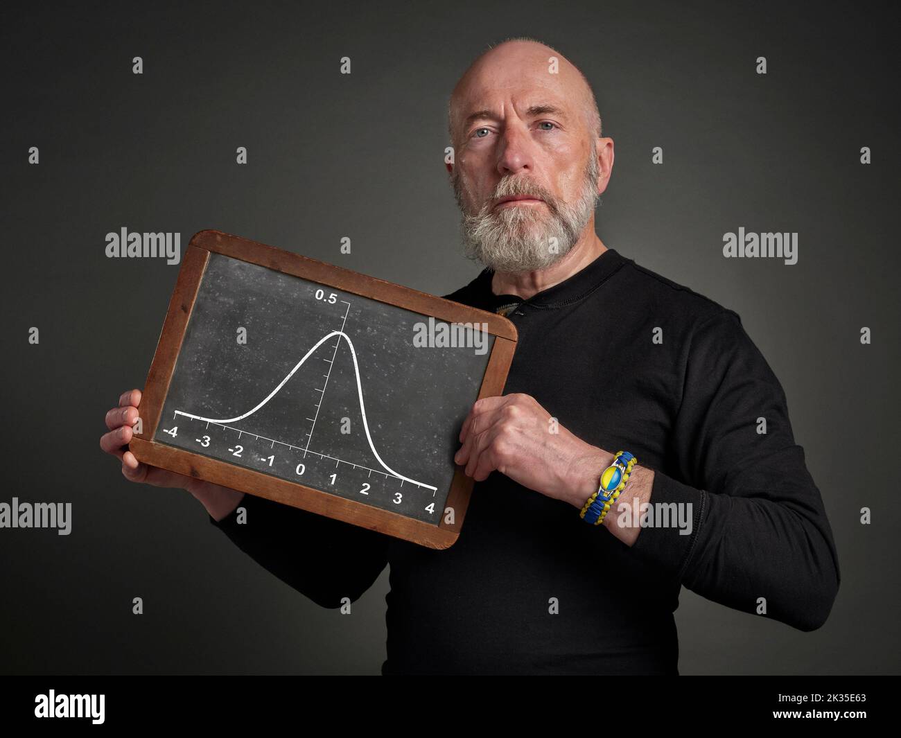 graph of Gaussian (bell) function on a slate blackboard held by a senior male, teacher or presenter - statistical concept Stock Photo