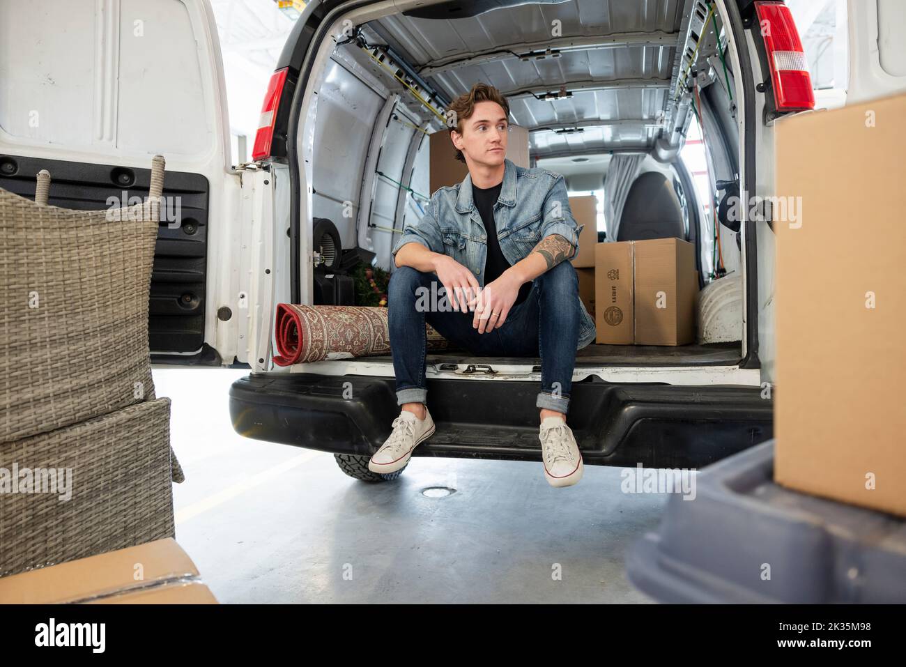 Young man taking a break from moving at back of van Stock Photo Alamy