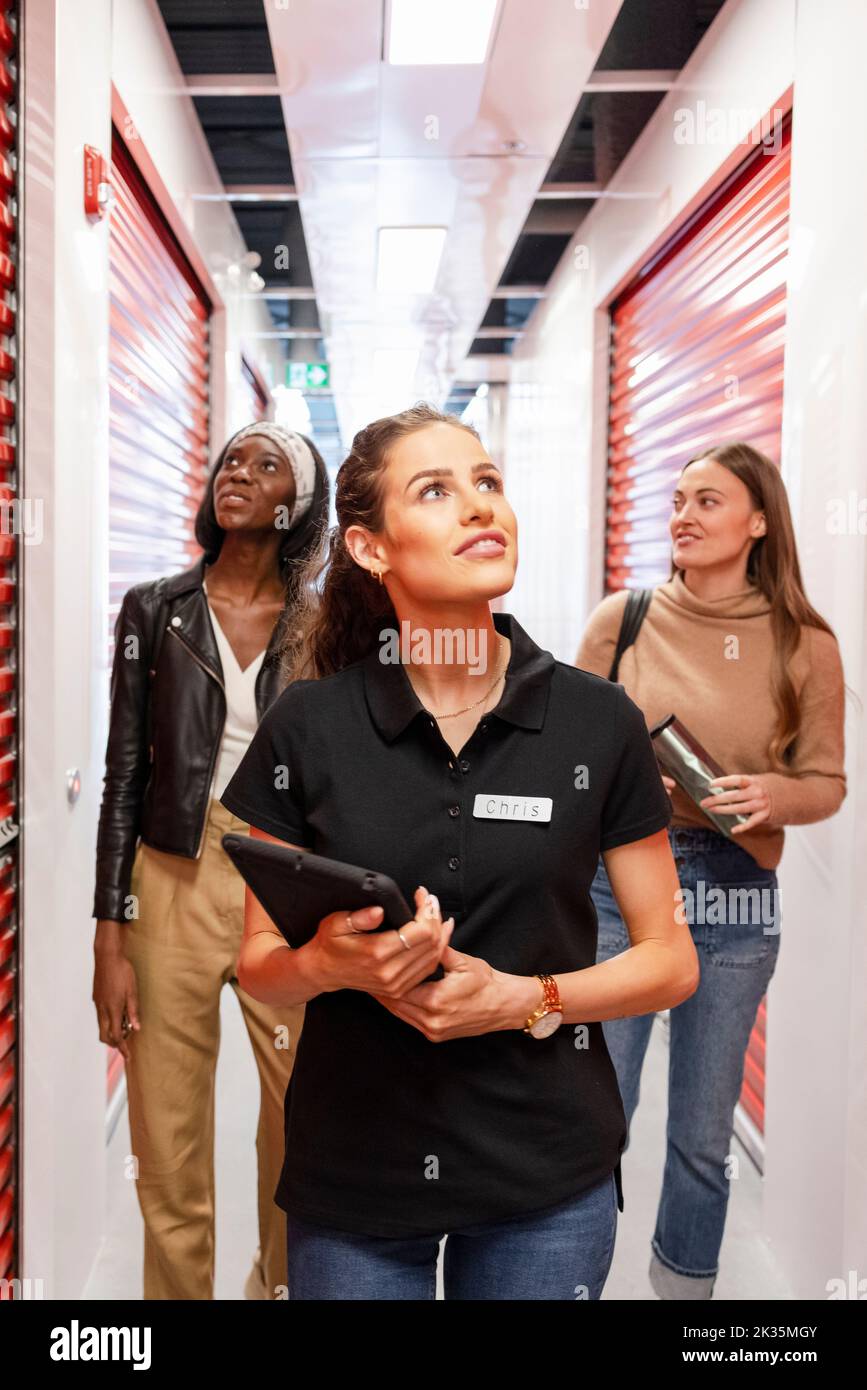 Storage facility worker giving tour to women Stock Photo Alamy
