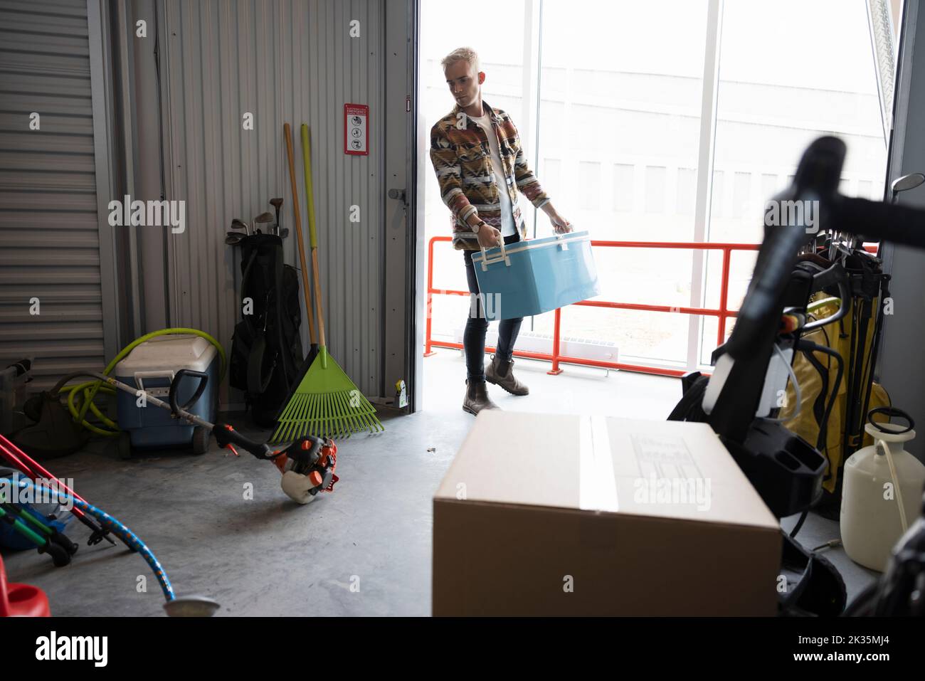 Young man moving cooler into storage facility locker Stock Photo