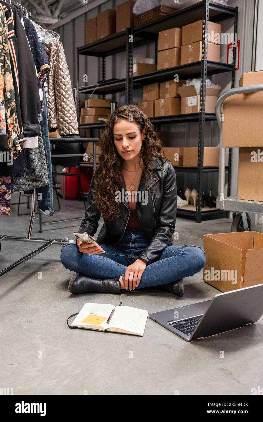 Female clothing consignment entrepreneur working in storage facility