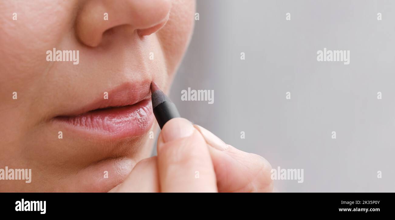 Banner applying makeup on face, closeup of lips with contour pencil. Professional Make-up. Lipstick Copy space. Real people natural lips detail Stock Photo