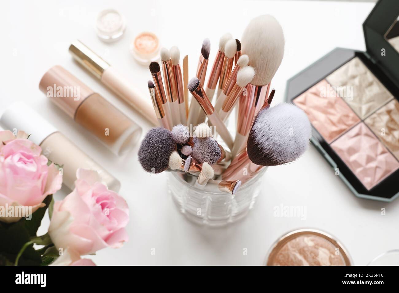 Professional makeup brushes and tools, make-up products set. Decorative cosmetics and makeup brushes on the table, top view on white. Flowers on Stock Photo