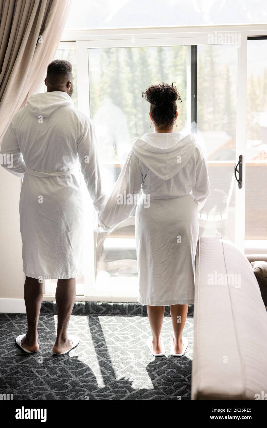 Couple in robes looking out of hotel room window Stock Photo Alamy