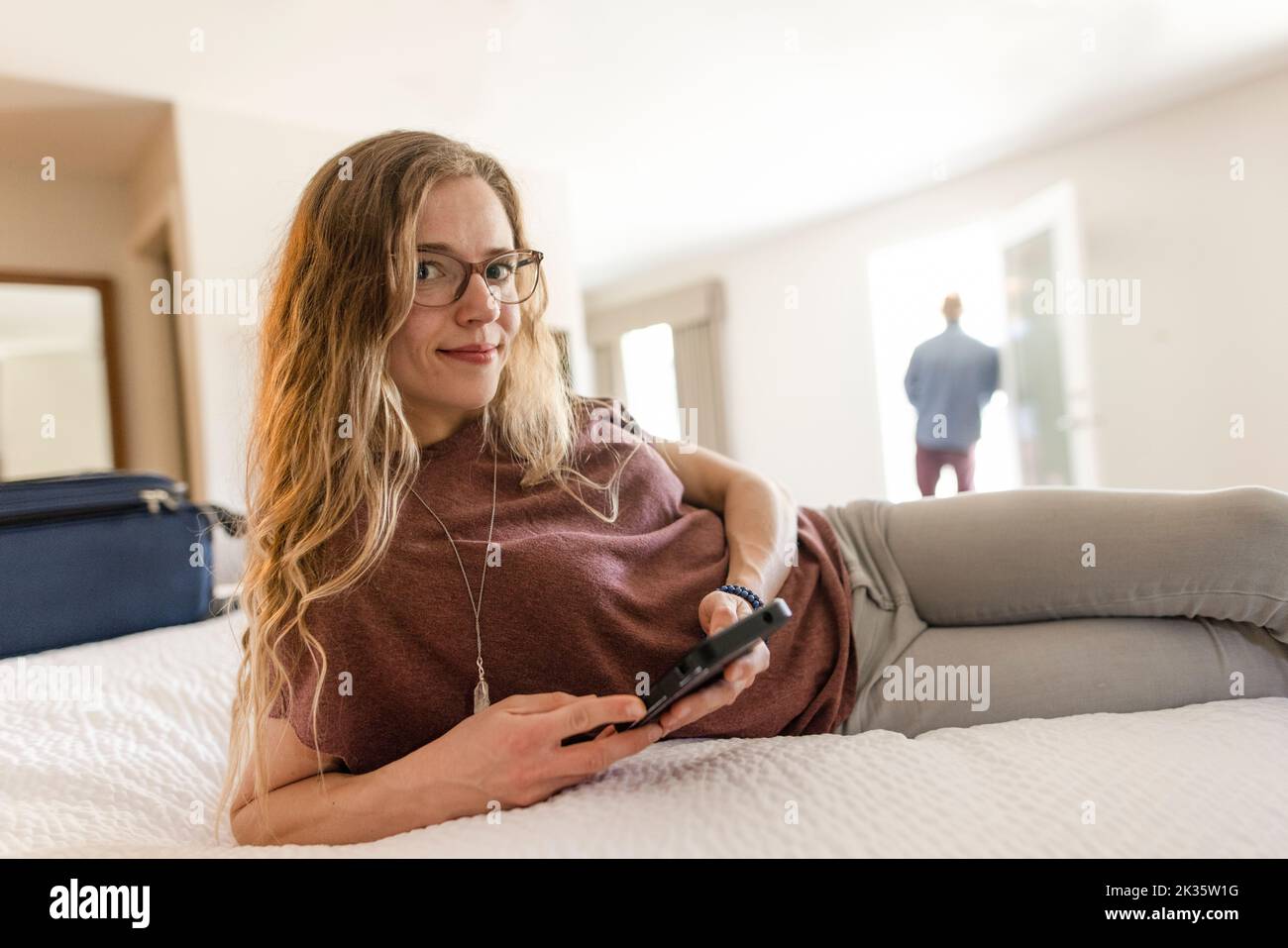 Portrait of woman looking at phone in hotel room Stock Photo