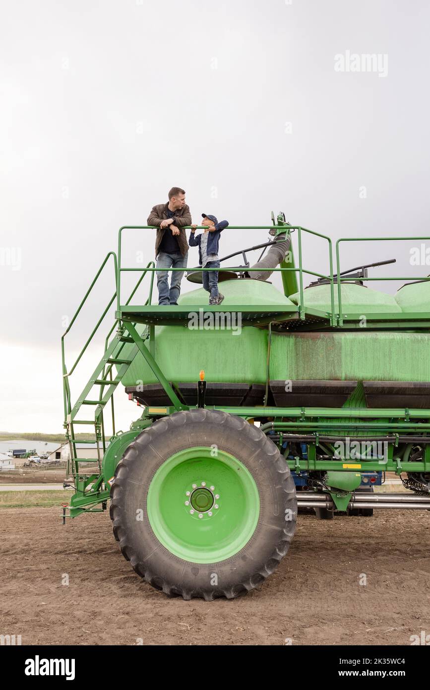 Father and son farmers on farming equipment platform Stock Photo Alamy