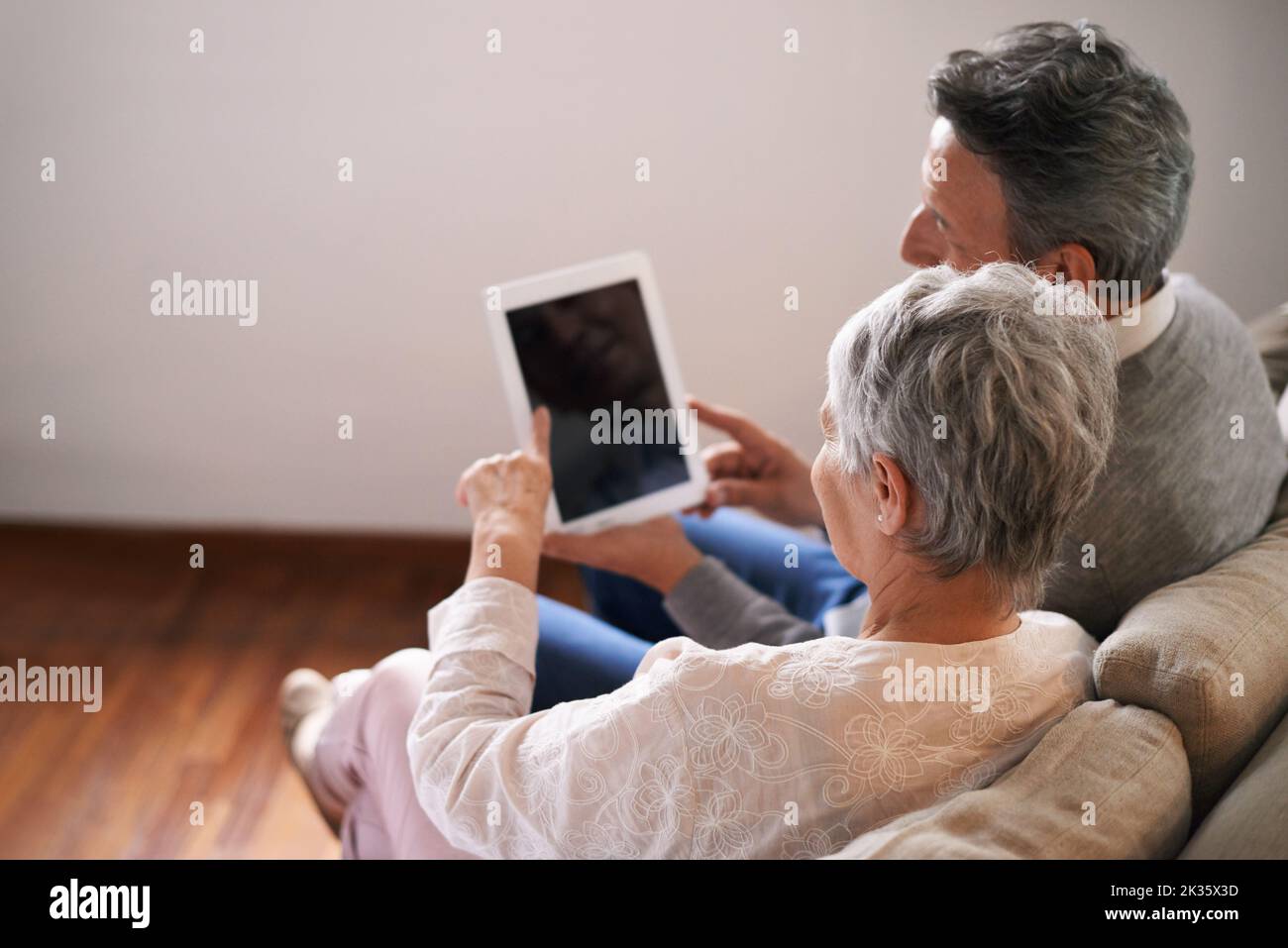 Staying connected to the family. A senior couple relaxing on the sofa with their digital tablet. Stock Photo
