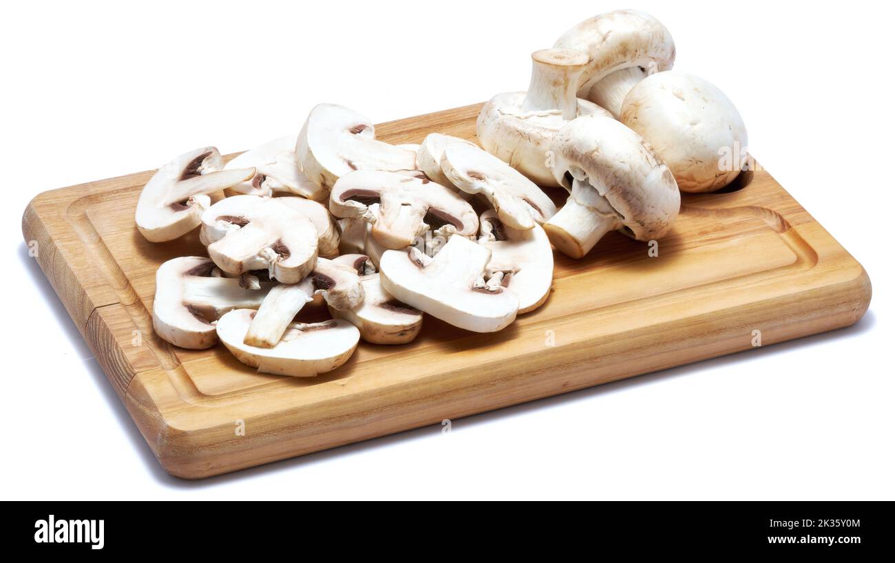 Sliced white champignon mushrooms on wooden cutting board isolated on white background Stock Photo