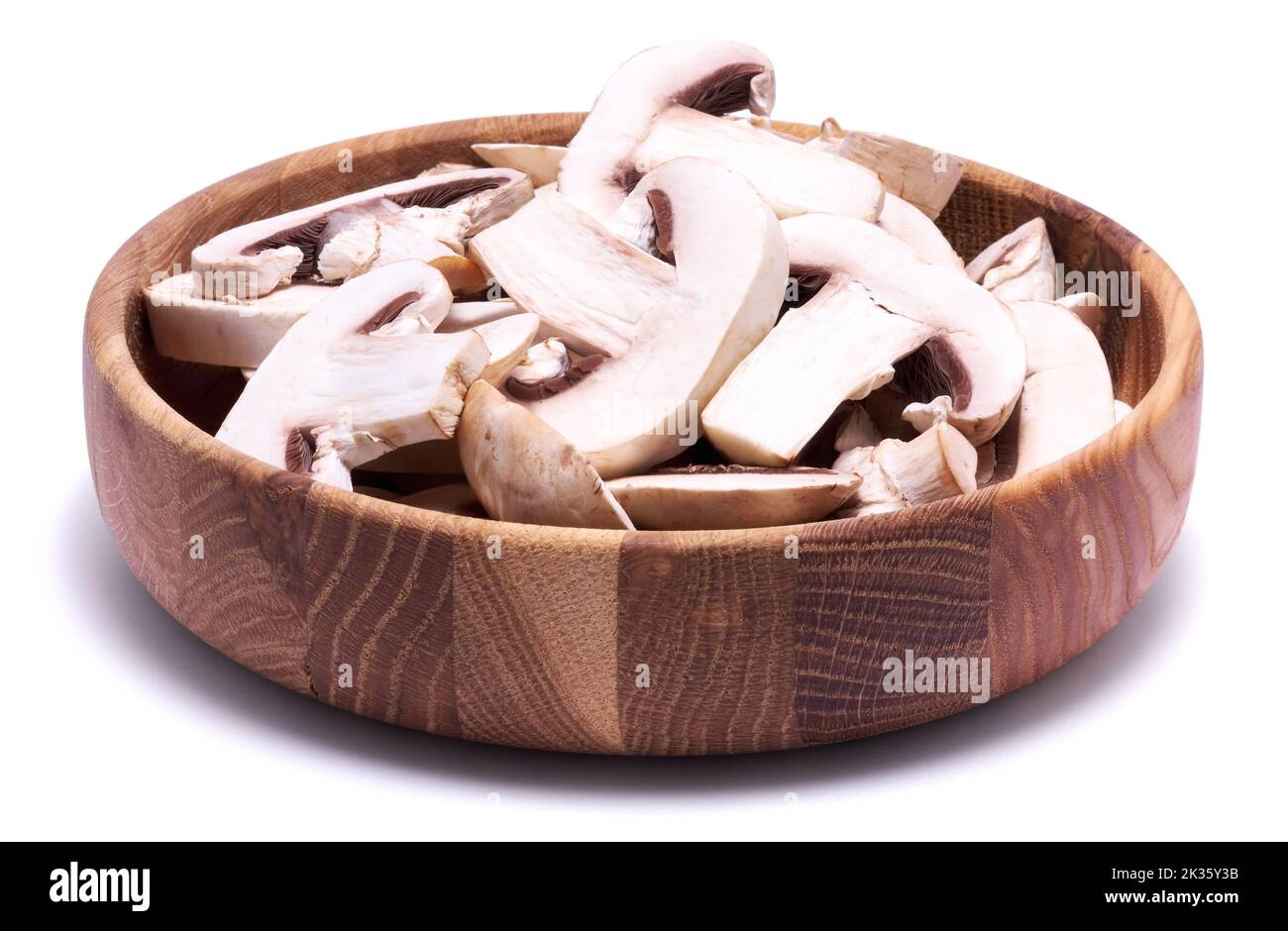 Sliced white champignon mushrooms in wooden bowl isolated on white background Stock Photo