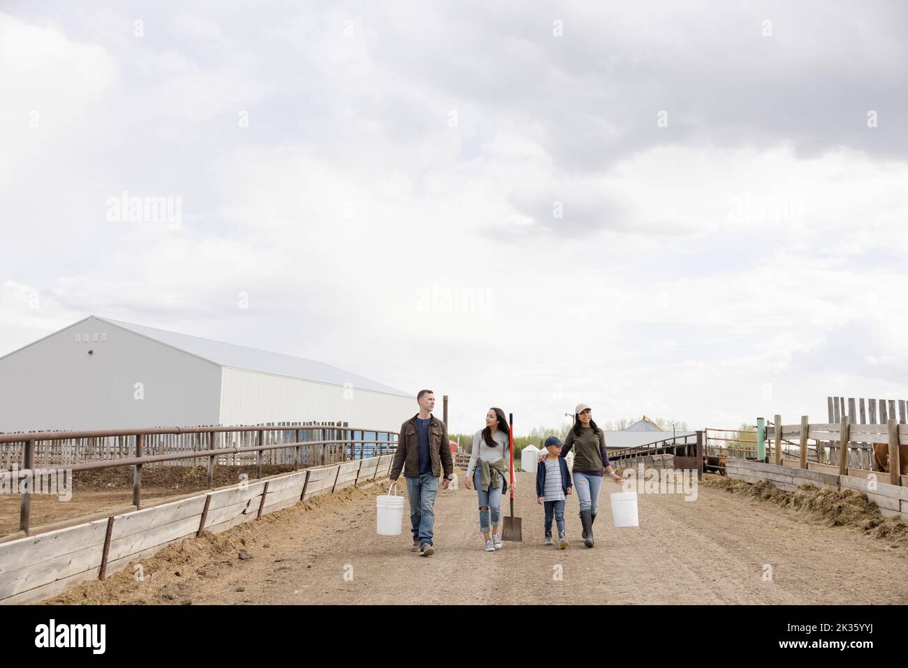 Farmer family carrying buckets and tools on dirt road on rural farm